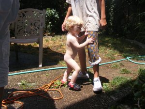 Na-Nakey boy playing with Zach in the backyard with the hose - still has his crocs on tho!